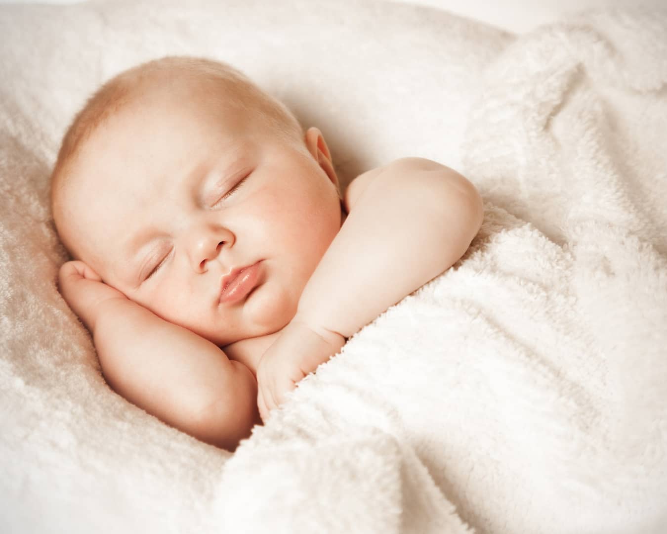 Infant peacefully napping in a sleep sack, a safe alternative to blankets for baby sleep routines